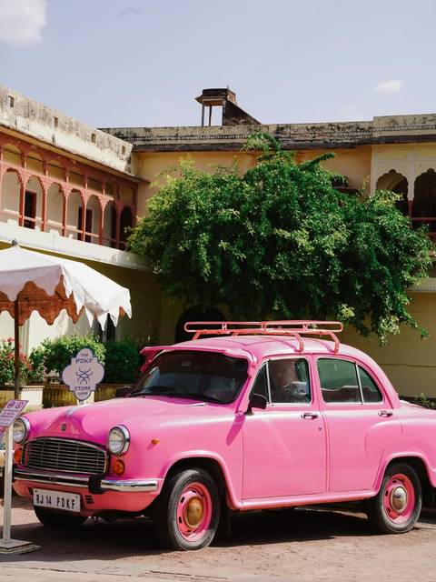 Pink car parked in front of an old building.