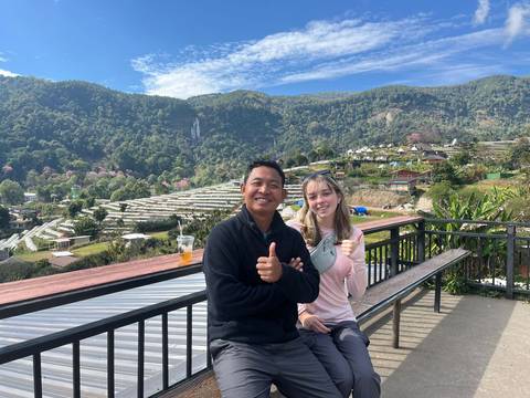       Two people sitting with a scenic background.
  