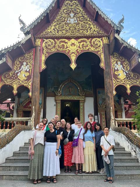       Group of people posing in front of a decorated building.
  