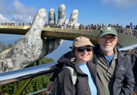 Couple standing in front of the Golden Bridge with giant hands.