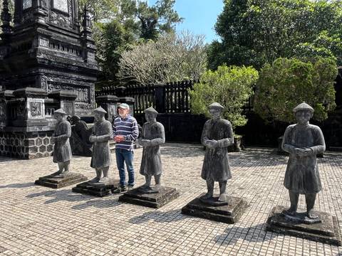 Man posing with a group of stone statues in a historical courtyard.