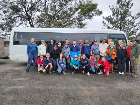 Group photo of people in front of a tour bus.