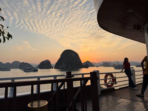 Woman on a boat enjoying sunset view of limestone karsts.