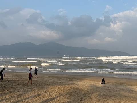 People relaxing on a sandy beach with waves in the background.