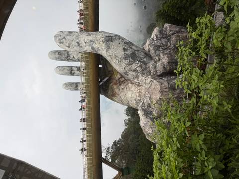 Giant hands holding a bridge with people walking on it.