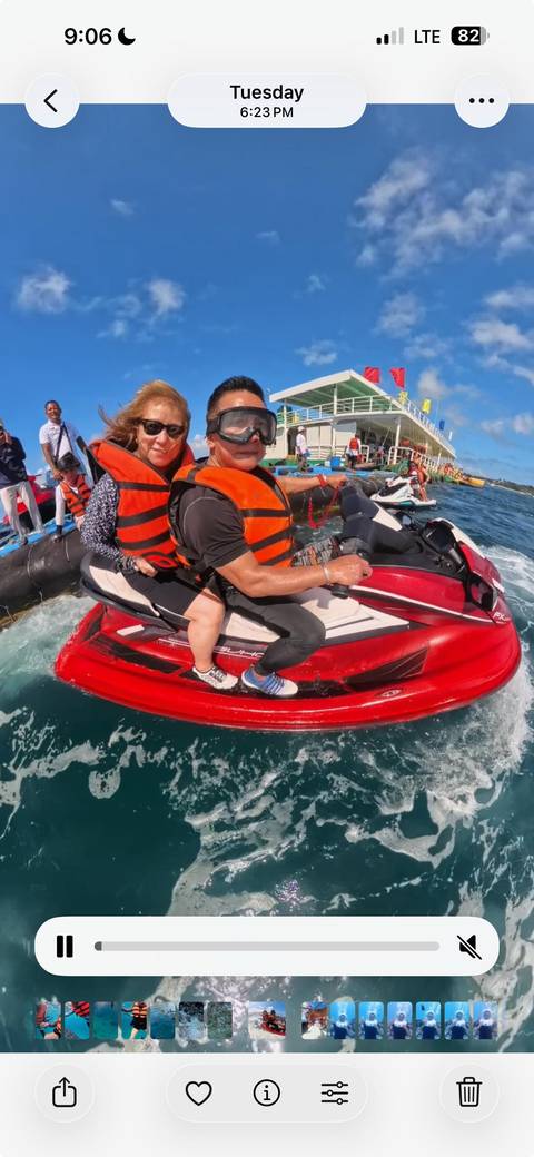       Two people riding a red jet ski on water, wearing life vests.
  