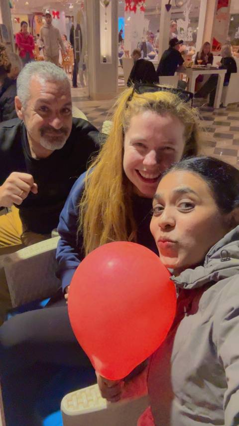 People smiling and holding a red balloon.