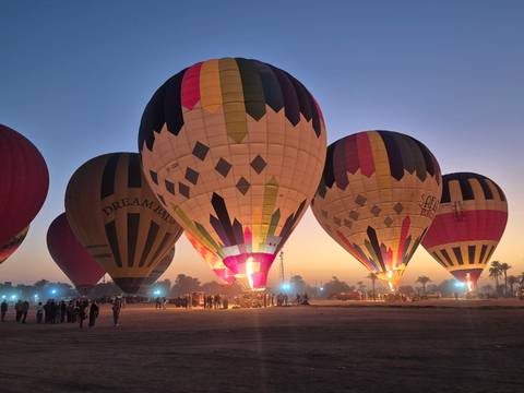 Hot air balloons being inflated at sunrise.