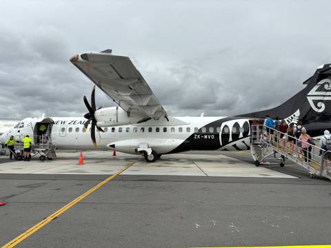       An airplane on the tarmac with people boarding.
  