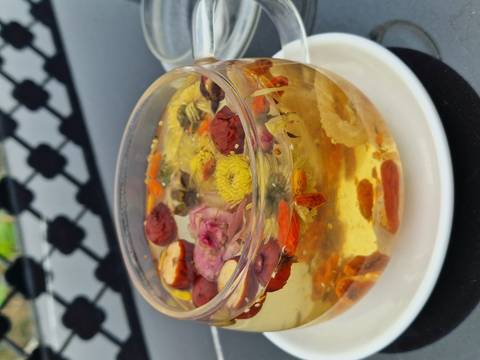 Close-up of a flower tea with various ingredients in a glass cup.