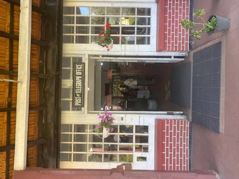       Entrance to a vintage Post and Telegraph office with people inside.
  