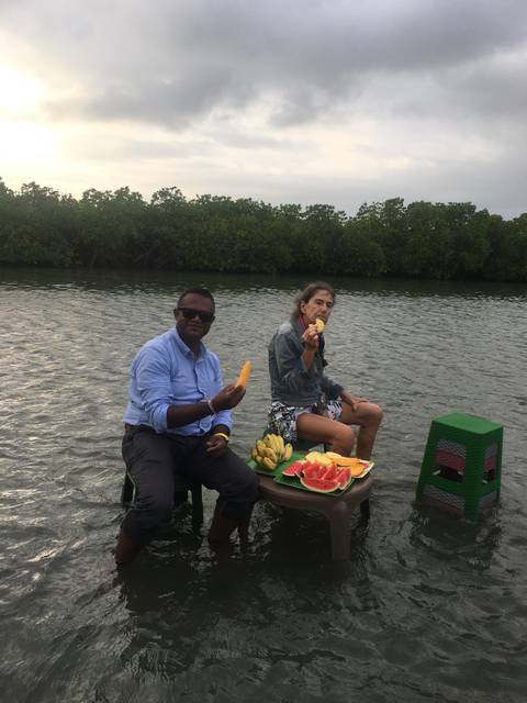       Two people enjoying fruit on chairs in a body of water.
  