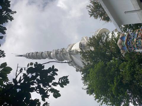       Intricate spire of a white temple surrounded by trees.
  