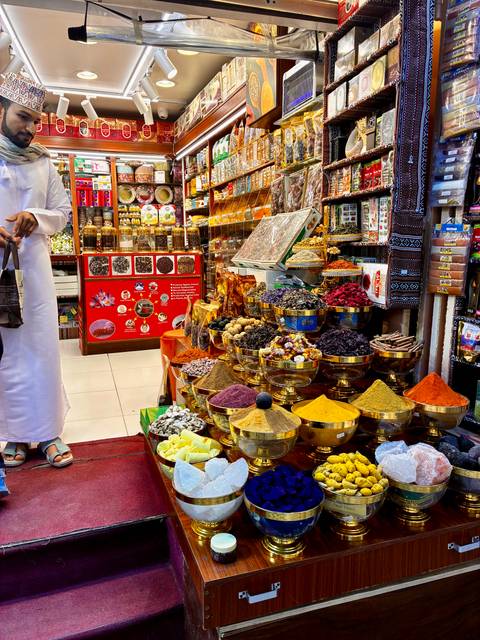       Colorful spice market with brightly colored spices in ornate bowls.
  