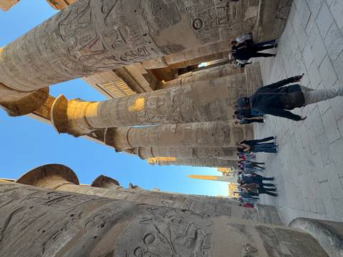 Tourists exploring an ancient Egyptian temple with columns.