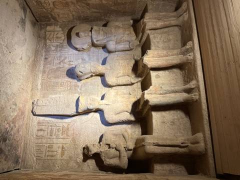 Inside a tomb with statues of seated Egyptian figures.