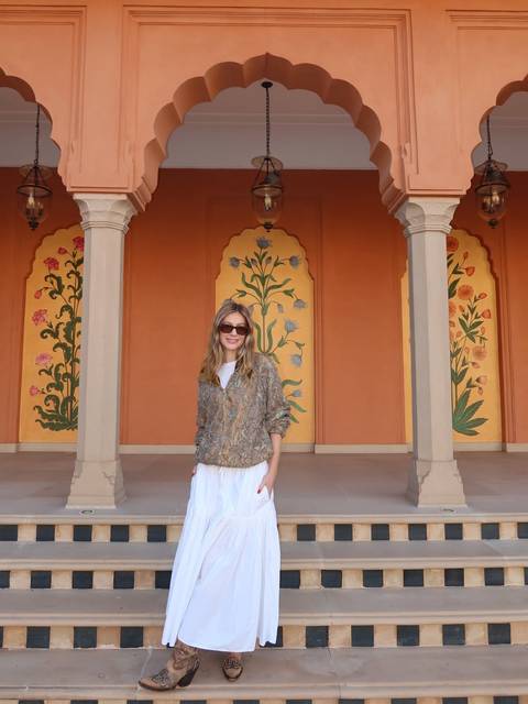 A woman posing in a vibrantly painted hallway with floral decorations.