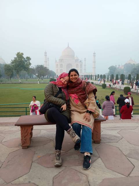 Two women posing with the Taj Mahal in the background.