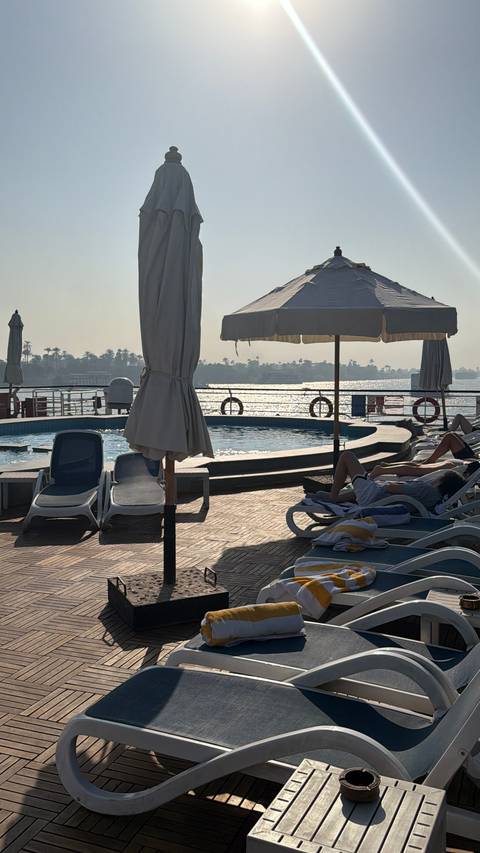 Sunbathing area with a pool on a boat, people relaxing.