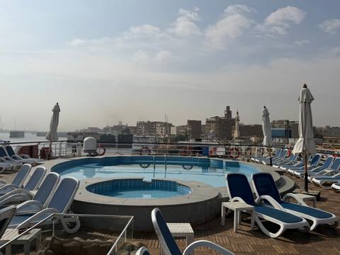 Sunbathing area with a pool, city view in the background.
