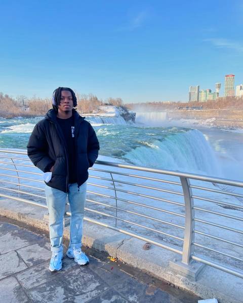 Person standing by a railing with Niagara Falls in the background.