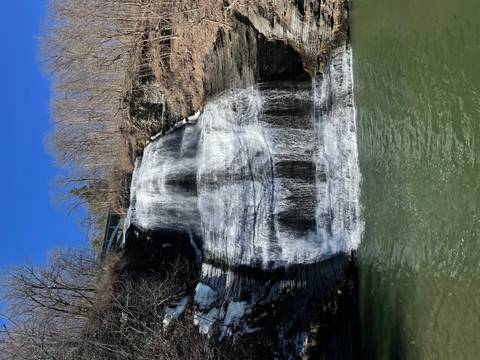 Waterfall cascading down a rocky cliff with clear blue sky.
