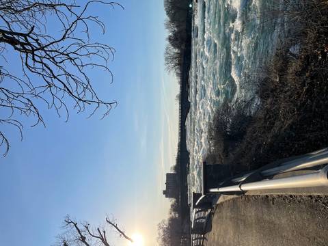 Wide river or rapid flowing under a bridge with distant city view.