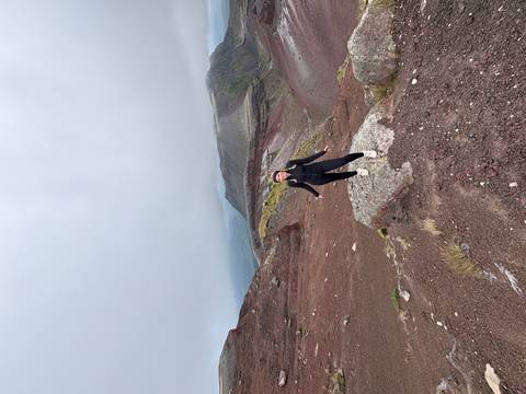       Individual posing on red volcanic terrain.
  