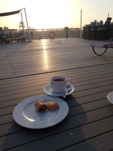 Cup of tea or coffee on a deck with sunrise.