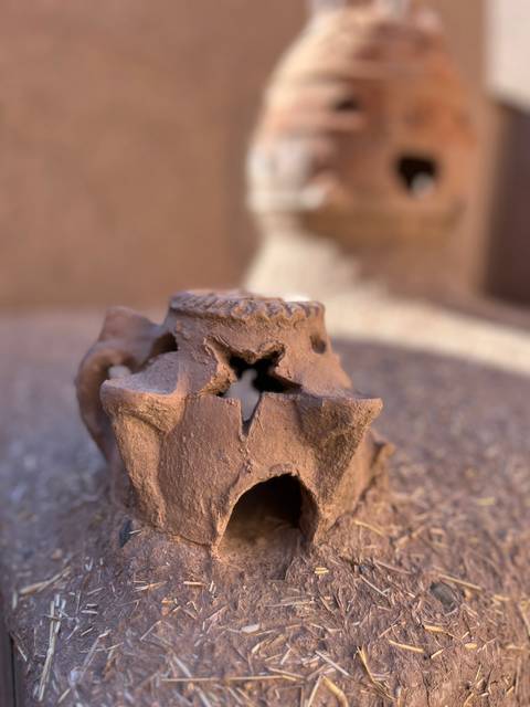 A close-up of a rustic clay ornament with a blurred background.