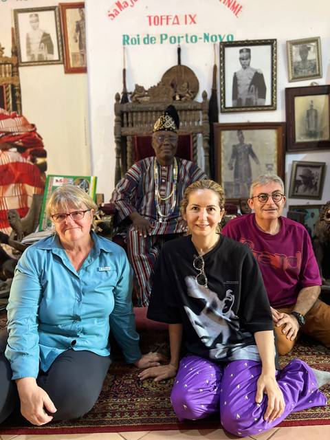 Group of people sitting inside a decorated room, posing for a photo.