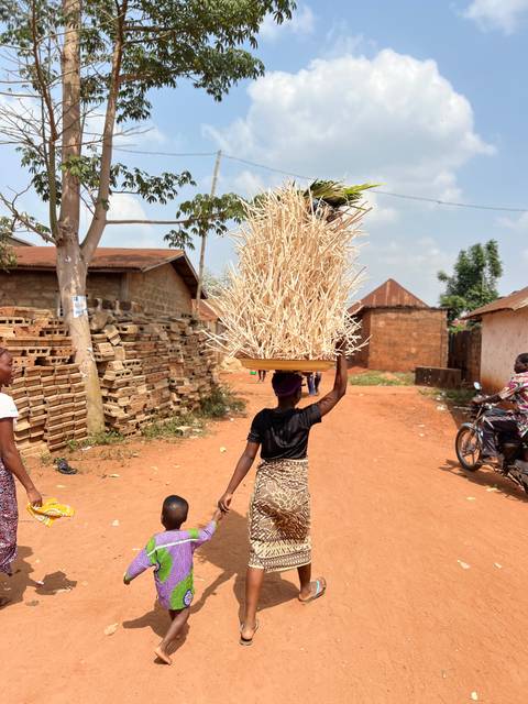 Woman carrying a large basket on her head in a village.