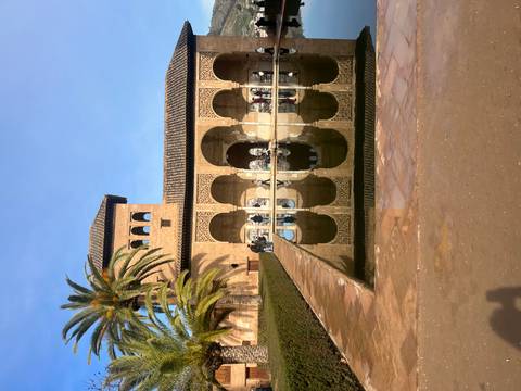 A historic courtyard with a reflective fountain and arches in Alhambra.