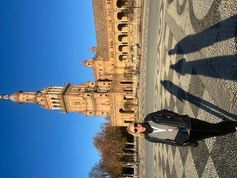 A woman standing in front of a plaza with a grand tower in Seville.
