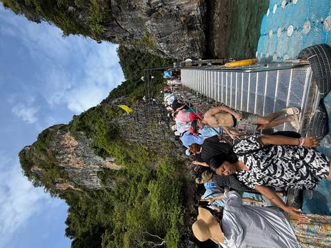 Tourists walking on a bridge towards a rocky island.