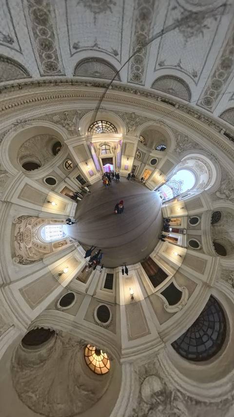       People walking in a large, ornately decorated atrium.
  