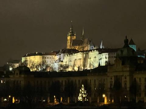 A blurry view of Prague Castle at night, illuminated.