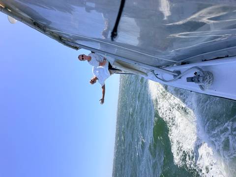 Two people enjoying a boat ride with ocean waves in the background.