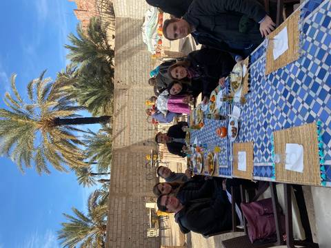 Group dining outdoors at a table with food and drinks.