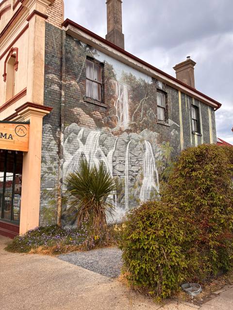 Artistic mural on a building featuring a waterfall.