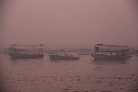 River with boats at sunset, in a pinkish hue.