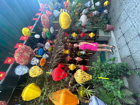 Woman standing under vibrant lanterns at a shop entrance.