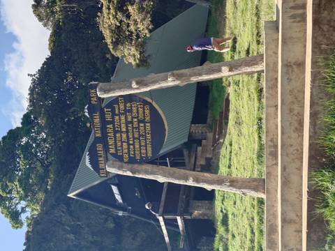       Signboard at Mandara Hut with people nearby.
  