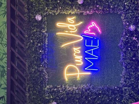 Neon sign reading 'Pura Vida MAE!' on a green background.