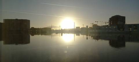 Sunrise over water with city buildings.