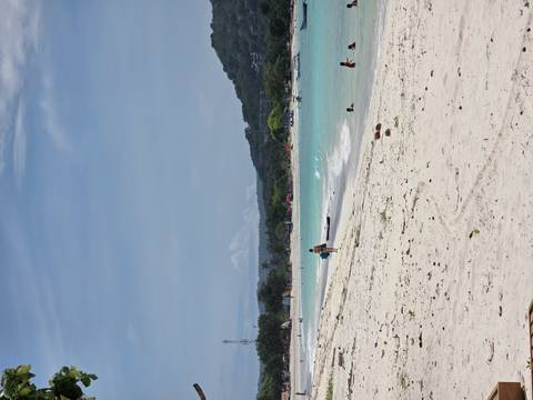 Beachgoers enjoying the sand and turquoise water at a beach.