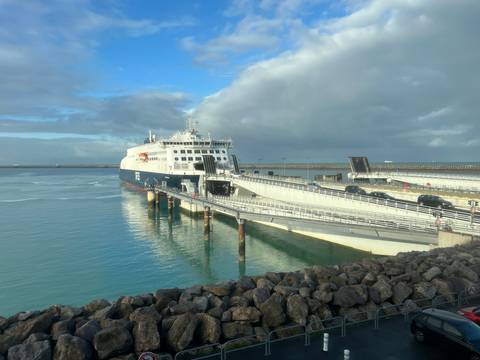 Ferry docked at a port with a cloudy sky.