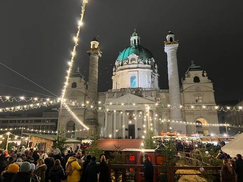       Baroque church lit at night with people in a holiday market setting.
  