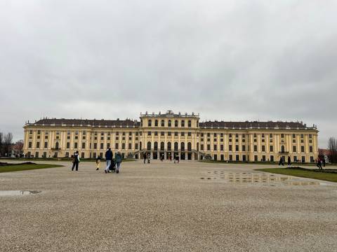       An expansive palace with tourists, overcast sky.
  