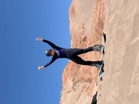 Woman sandboarding in a desert landscape.